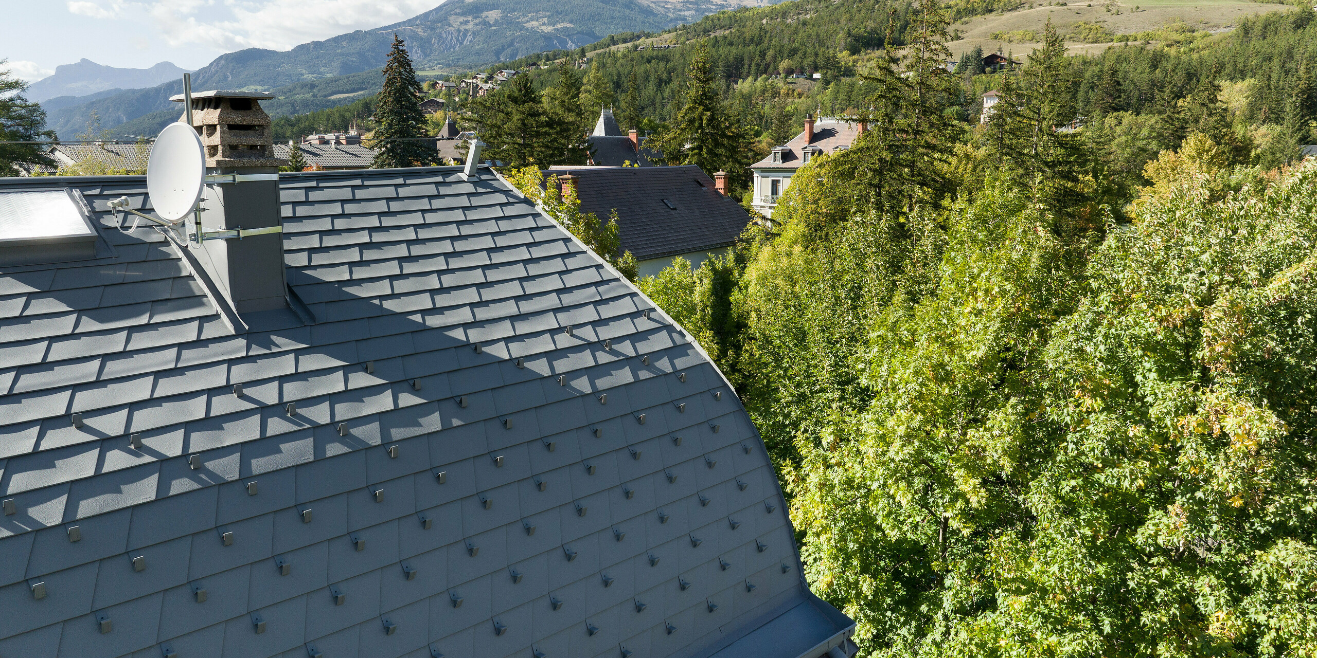 Die großflächige Dachlandschaft eines Anwesens in Barcelonnette, Frankreich wurde mit der PREFA Dachschindel in P.10 Hellgrau saniert. 