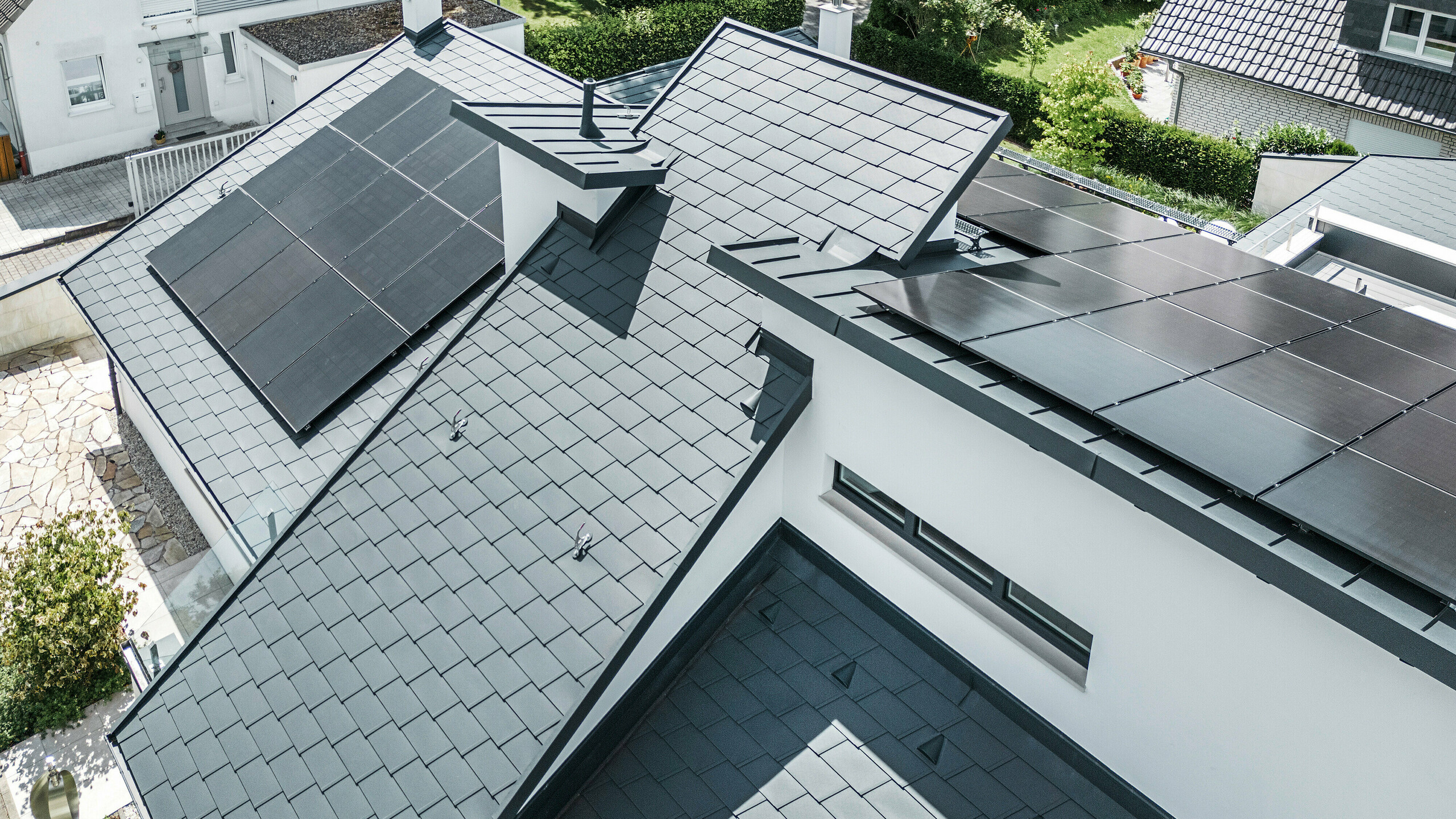 Fågelperspektiv på de olika nivåerna på taket till ett modernt enfamiljshus i Dortmund som utrustades med PREFA DS.19 och PREFALZ takshingel i färgen P.10 antracit samt en storskalig solcellsanläggning.