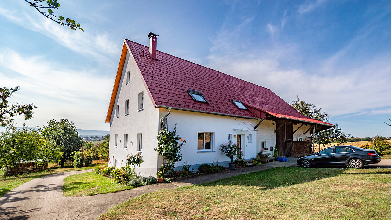 Gammal liten gård på landet, vackert renoverad med PREFA takplattor i oxidrött.