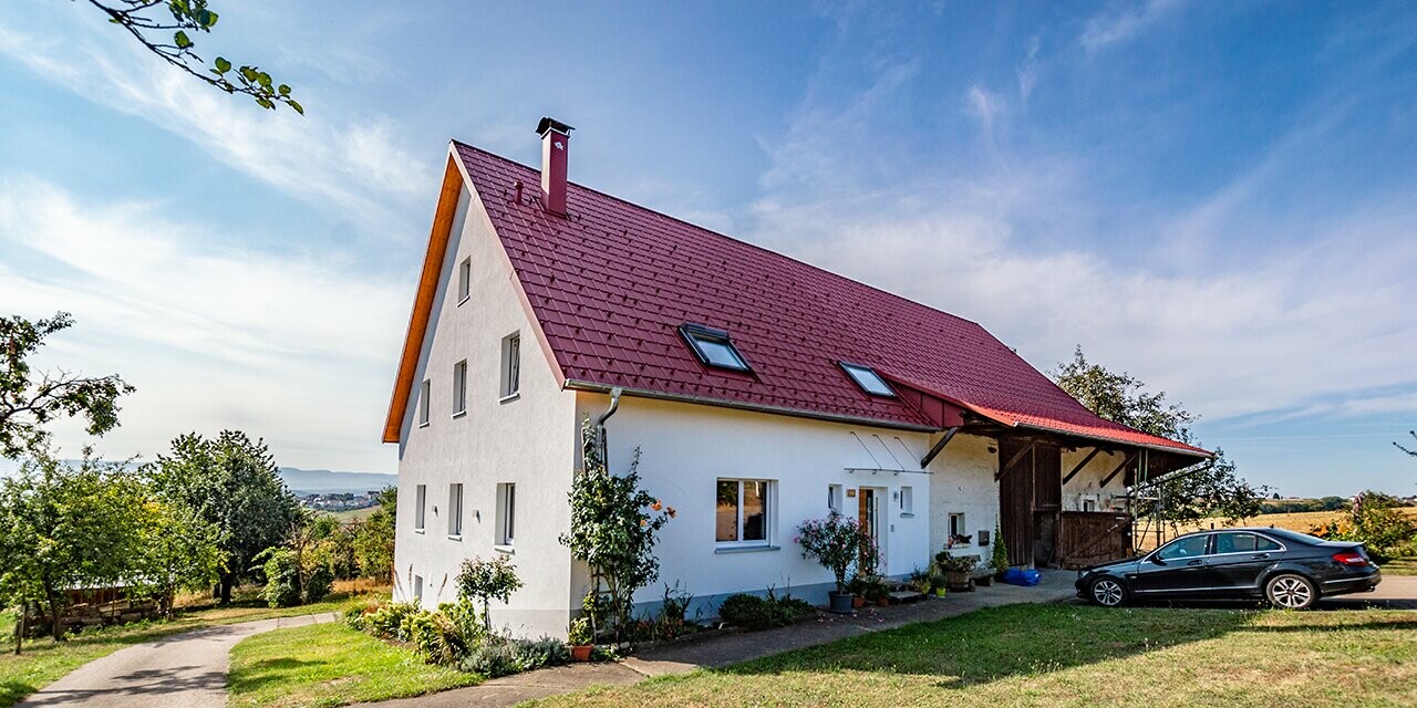 Gammal liten gård på landet, vackert renoverad med PREFA takplattor i oxidrött.