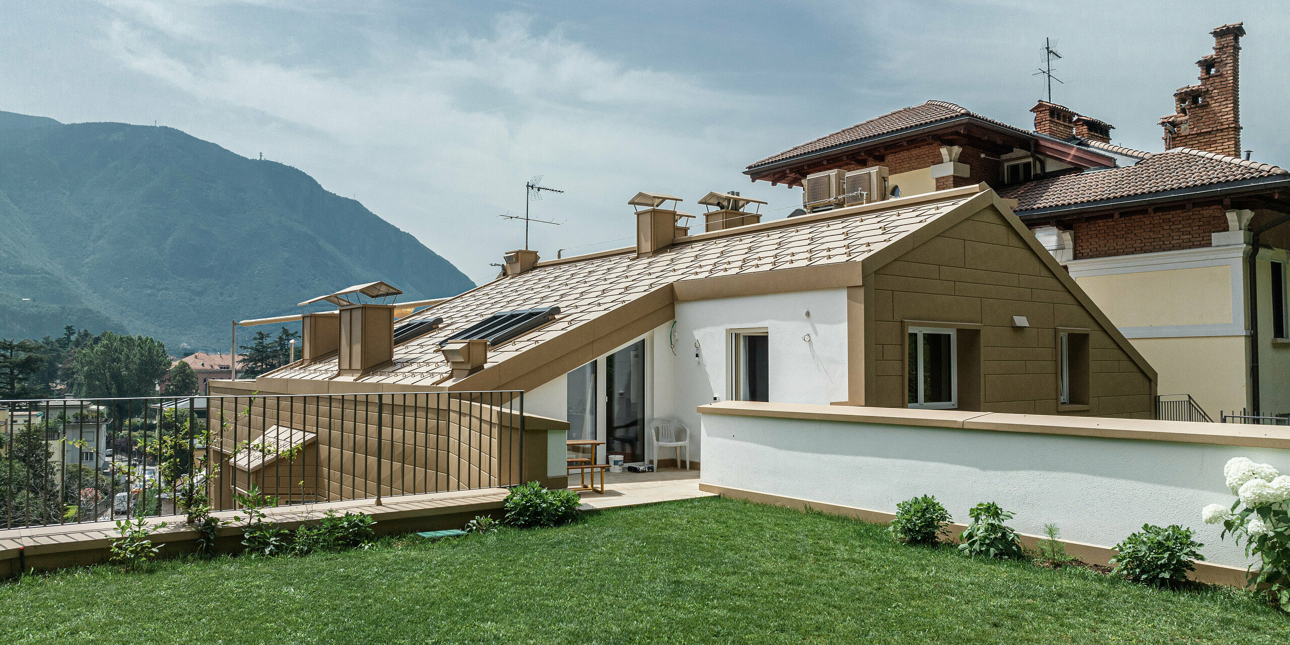 Die Villa Laura zeigt sich mit einem PREFA Dachpaneel FX.12 in Sandbraun, das nahtlos in die sanfte Grünfläche und die malerische Berglandschaft Südtirols übergeht. Die Kombination von traditioneller Architektur mit modernen, langlebigen Aluminiumelementen von PREFA unterstreicht die ästhetische Vielfalt und Funktionalität der Baumaterialien. Dieses Zuhause bietet mit seiner sorgfältig konzipierten Außengestaltung und der harmonischen Einbettung in die natürliche Umgebung ein perfektes Beispiel für die Symbiose aus Form, Funktion und Natur.