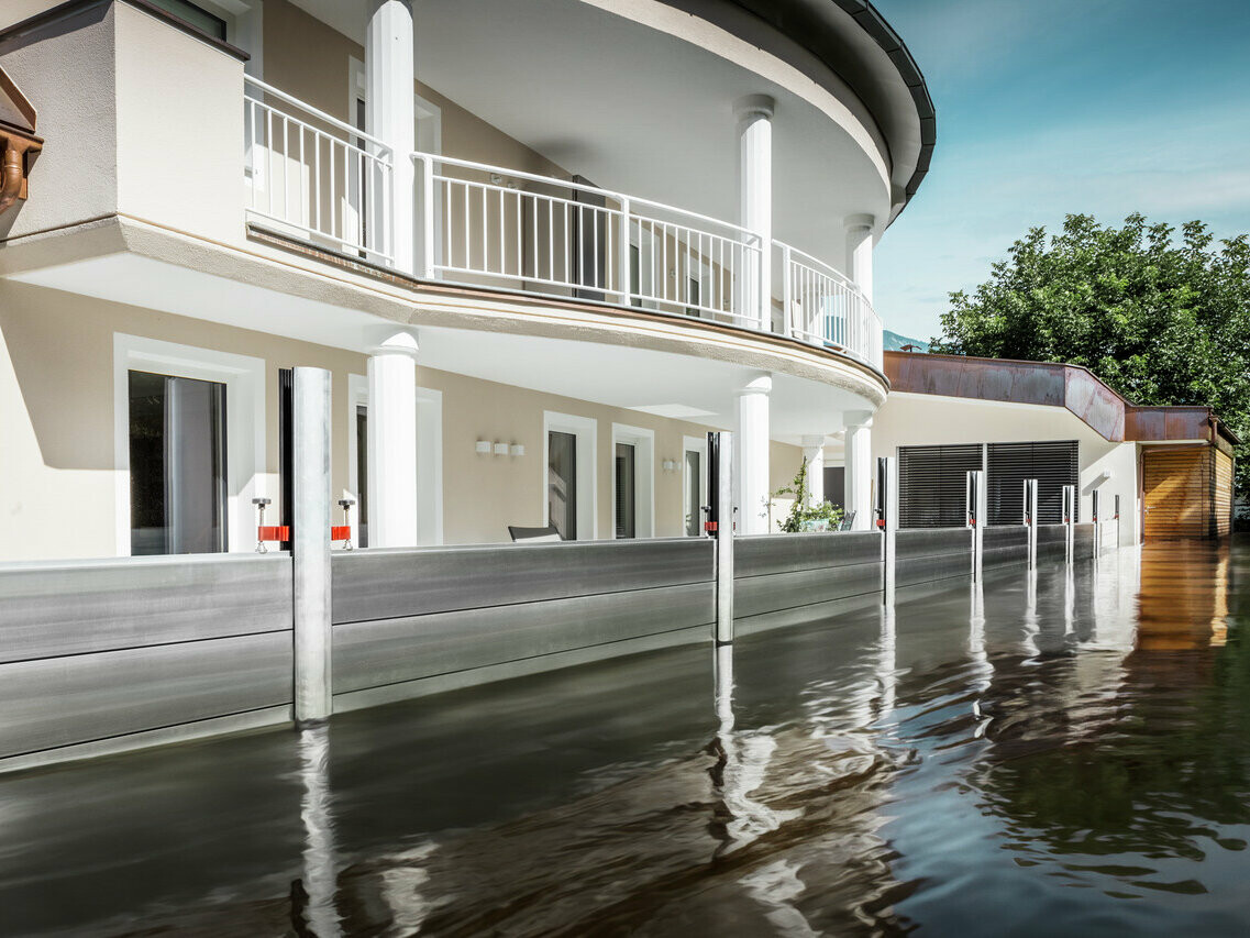 Bilden visar ett fristående hus med balkong. PREFA översvämningsskyddssystem skyddar huset från de redan stigande vattenmassorna.