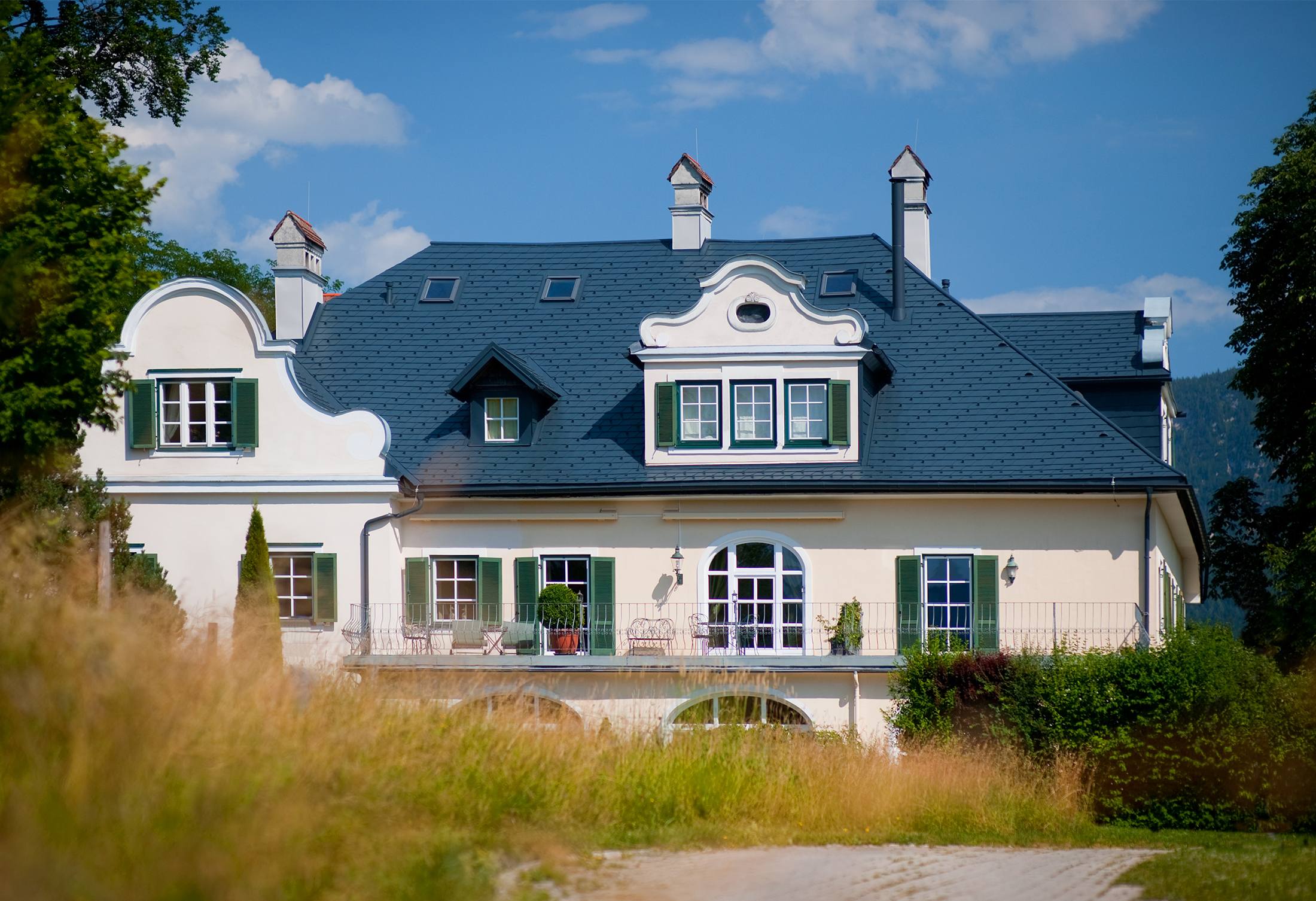 Blick aus der Ferne auf eine Villa in Bad Aussee, Österreich. Das Dach der Villa wurde mit robusten PREFA Dachschindeln in der Farbe P.10 Anthrazit verkleidet.